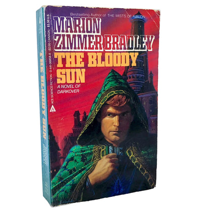 The Bloody Sun paperback novel by Marion Zimmer Bradley, showing the front cover and spine on a white background with a marble surface.