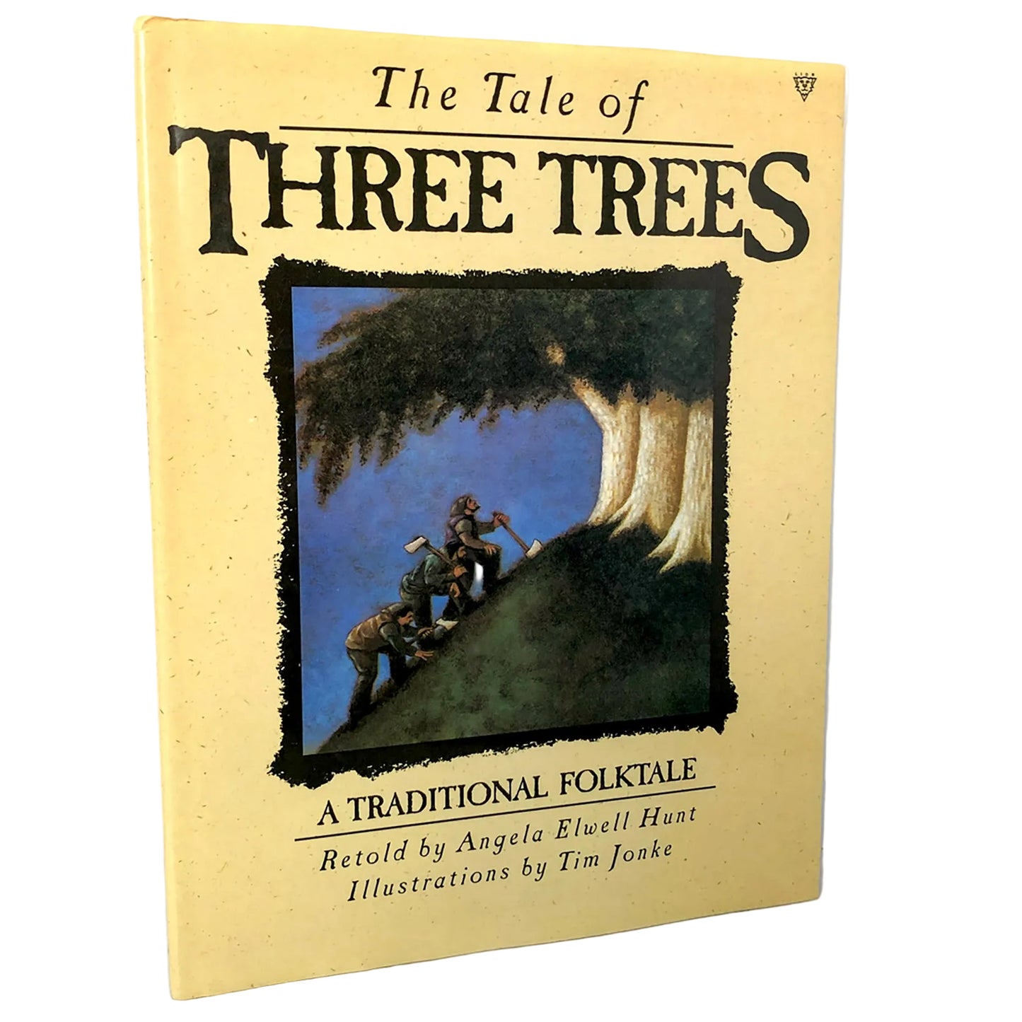 The Tale of Three Trees book cover, featuring a pale yellow background with large black title text and an illustration of three figures climbing a tree, photographed against a white wall and light stone surface.