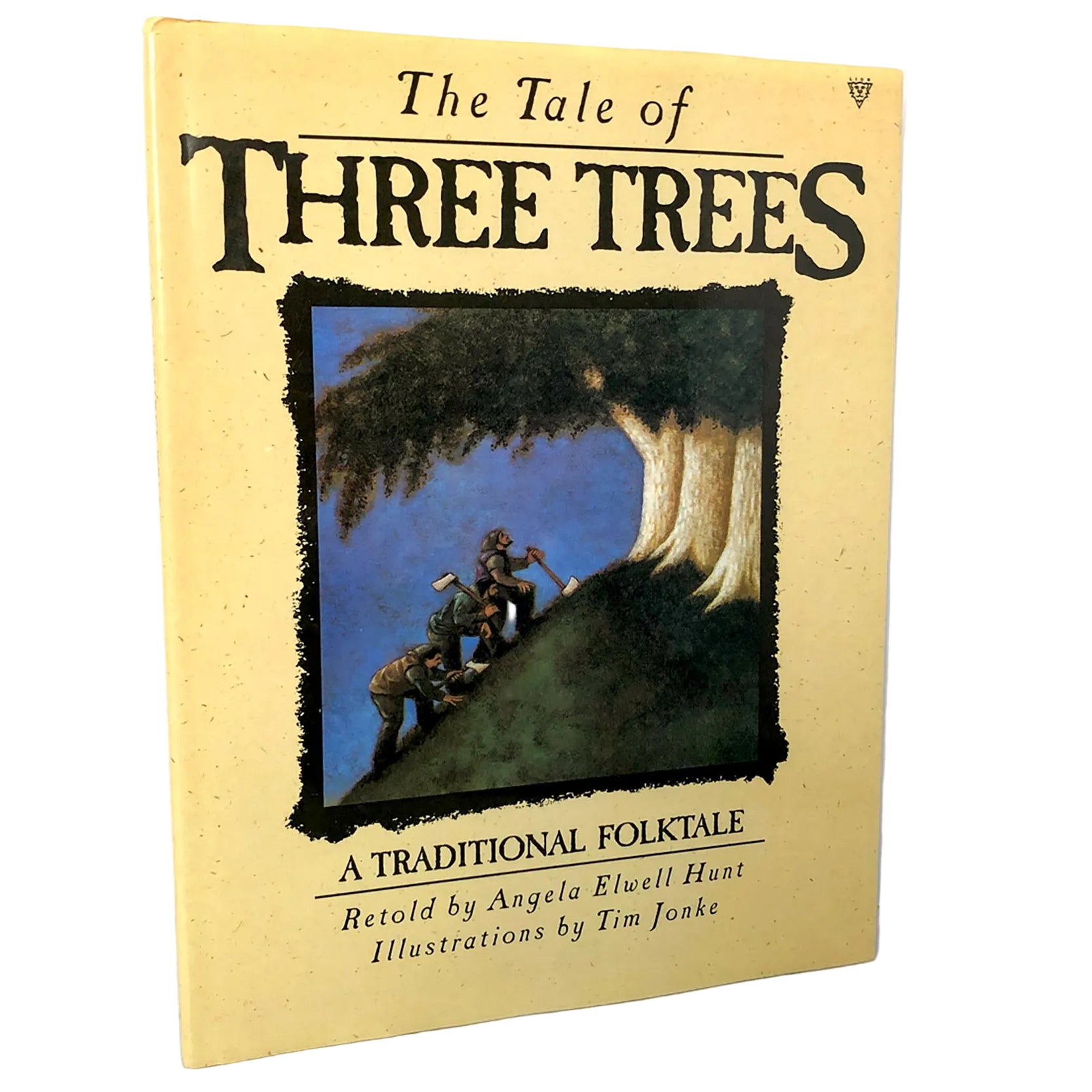 The Tale of Three Trees book cover, featuring a pale yellow background with large black title text and an illustration of three figures climbing a tree, photographed against a white wall and light stone surface.