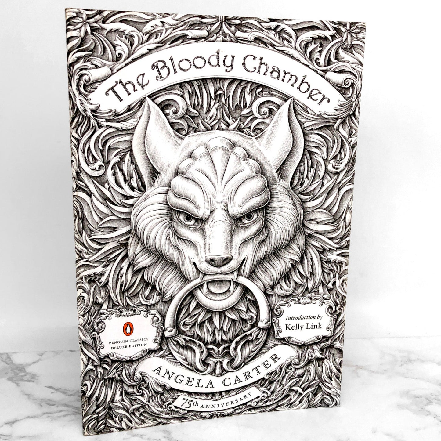 A paperback edition of 'The Bloody Chamber & Other Stories' by Angela Carter, featuring a black and white illustration of a wolf's head on the cover.