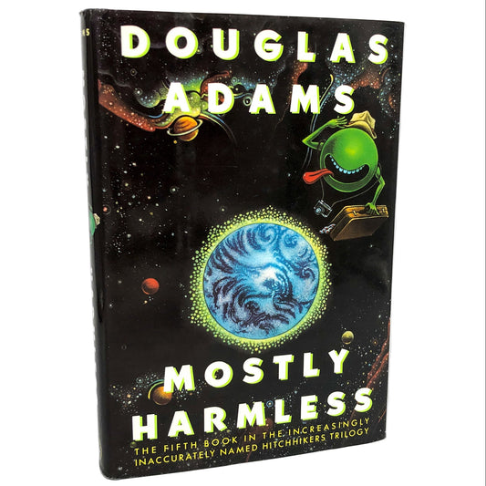 The cover of 'Mostly Harmless' by Douglas Adams features a black background with a colorful illustration of an alien character in a spacesuit, with a depiction of a planet and stars in the background. The book is labeled as the 'Hitchhiker's Guide to the Galaxy #5' and is described as a first edition, hardcover with dust jacket.